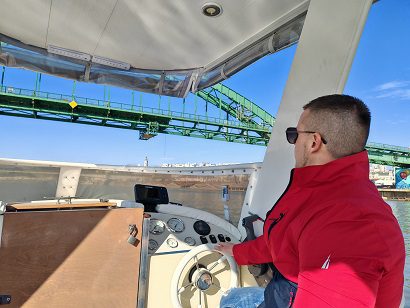Licensed boat captain at the helm of a cruising boat near a bridge in Belgrade