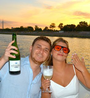Bride in a white dress posing on the bow of a luxury boat with the Ada Bridge in Belgrade