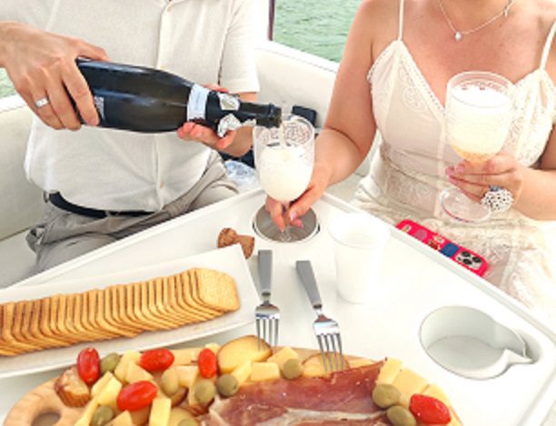 Couple enjoying champagne and food platter inside a luxury boat cabin in Belgrade